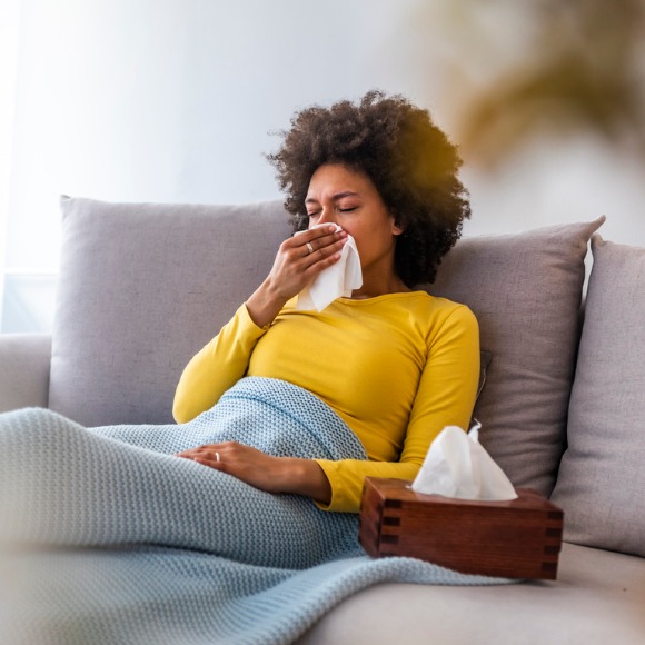 woman on sofa blowing nose box of tissues